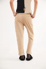 Pantalón recto de tiro medio confeccionado en pana con lycra. Presenta pinzas frontales, bolsillos laterales y traseros, y cierre con botón dorado. El diseño destaca por el detalle de paño espigado en el interior del ruedo, visible al doblarlo, y un pin bordado decorativo en el bolsillo delantero.