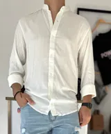 Camisa blanca de manga larga con cuello mao y cierre frontal con botones.