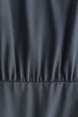 Vestido corto de punto elástico color gris oscuro, con escote redondo, mangas largas, cuerpo holgado y pollera entallada con frunces laterales.