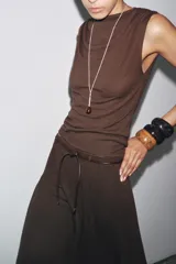 Top de tejido punto color marrón oscuro, con escote asimétrico tipo *one-shoulder* y drapeado frontal.