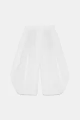 Pantalón blanco de tiro alto con cintura elástica ajustable mediante lazada interior. Presenta bolsillos laterales y un bajo con mucho volumen, creando una silueta redondeada.