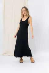 Vestido midi negro sin mangas con escote redondo, confeccionado en tejido fluido tipo seda con detalle de flecos en el ruedo.