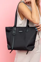 Bolso negro tipo tote bag con manijas cortas y cierre superior.