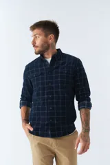 Camisa de manga larga confeccionada en pana, con diseño de cuadros en tonos azul marino. Presenta cuello clásico, cierre frontal con botones y dos bolsillos con solapa y botón en el pecho.