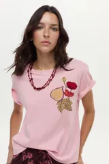 Remera de algodón color rosado, de manga corta, con cuello redondo y detalle de estampa y bordado frontal con diseño de una flor y una higuera.