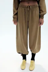 Pantalón fluido confeccionado en mezcla de modal, de tiro medio con cintura elástica ajustable con cordón y bolsillos laterales, en color tostado.