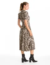 Vestido midi de seda fría con estampado animal print. Presenta cuello con solapa, escote en V con cierre frontal de botones, mangas cortas con terminación fruncida y lazo de ajuste en la cintura.