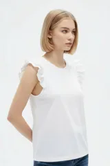 Remera de algodón color blanco, de corte al cuerpo, con cuello redondo y detalles de volados en las sisas.
