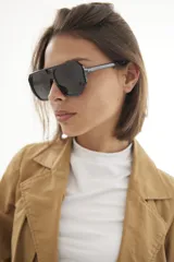 Lentes de sol con armazón de policarbonato negro y cristales tonalidad ámbar, con diseño de puente doble estilo aviador.