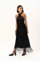 Vestido midi de satén color negro, con escote halter cruzado y ruedo terminado en flecos largos.