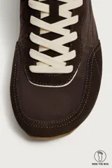 Zapatilla deportiva barefoot de hombre, confeccionada en combinación de piezas de piel con acabado serraje en color marrón, con cordones y suela fina de goma en contraste.