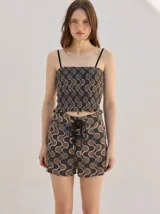Short holgado de cintura alta con pretina integrada, cordón ajustable delantero y estampado geométrico en tonos rojos y beige.