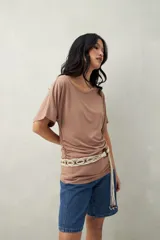 Remera negra de manga corta, confeccionada en modal, con cuello bote y frunces laterales.