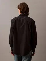 Camisa negra de manga larga con cuello abotonado y logo de Calvin Klein bordado en el pecho.