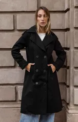 Trench clásico de largo midi en color beige, con diseño de doble abotonadura, solapas amplias, detalles en hombros y correas ajustables en los puños.