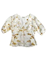 Camisa color mostaza de lino con corte en la cintura y abotonadura central. Tiene manga abullonada con detalle de elástico en puños.