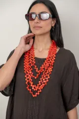 Collar multicapa de cuentas naranjas y rojas con diseño en cascada.