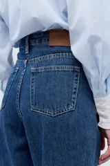 Jean de calce mom, 100% algodón, con lavado azul medio y bordado exclusivo en el interior de la cintura.