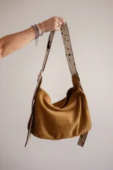 Bolso tipo hobo de gamuza color naranja quemado, con correa ancha de tela color bordó.