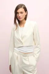 Blazer corto color blanco hueso, de manga larga, con solapa y bolsillo de pecho en tela brillosa.