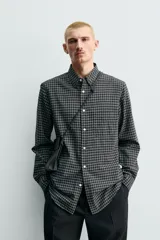 Camisa de corte regular fit confeccionada en una mezcla de lana y algodón. Presenta un diseño de cuadros pequeños, cuello solapa, manga larga con puños abotonados y cierre frontal con botones. Incluye un bolsillo en el pecho.