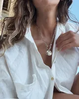 Collar de cadena de eslabones alargados con cierre frontal tipo T y dije circular de textura rústica e irregular.