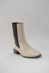 Botas de cuero color beige con elásticos laterales negros, taco cuadrado y punta cuadrada.