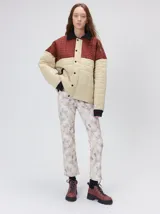 Campera acolchada de diseño colorblock, con el pecho y hombros en tono bordó y el cuerpo y mangas en color beige. Presenta cuello camisero y puños de pana negra, cierre frontal oculto con botones a presión y costuras pespuntadas en patrón cuadriculado.