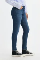 Jeans de tiro medio, color azul oscuro, de corte ajustado en cadera y muslos, y pierna skinny.