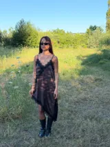 Vestido corto tipo lencero de seda color blanco, con detalles de encaje negro en el escote en V y en el ruedo asimétrico. Presenta breteles finos ajustables y una caída fluida.