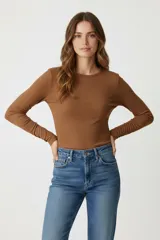 Remera de manga larga color blanco hueso, de tejido acanalado y corte ajustado al cuerpo, con cuello redondo.