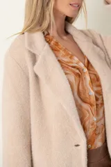 Blazer italiano color beige, de corte recto, con solapas de muesca, cierre de un botón y bolsillos simulados.