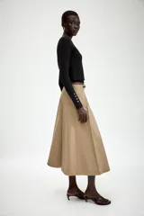 Falda midi de tiro alto en color beige, con diseño evasé y pliegues laterales. Incluye un cinturón fino a contraste en color negro con hebilla metálica y cierre frontal con cremallera y gancho.