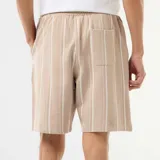 Bermuda beige a rayas blancas, de corte recto, con cintura elástica y cordón ajustable.