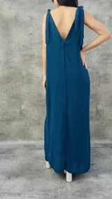 Vestido largo color verde azulado, con breteles finos que se atan en los hombros, escote en V en la espalda y tajo lateral.
