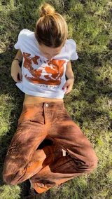 Pantalón de tiro medio y corte recto, con un acabado rústico y estampado artesanal en tonos tierra que simula texturas naturales. Presenta cierre frontal con botón y bolsillos laterales.