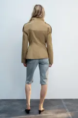 Cazadora de estilo militar en color tostado, con cuello subido, cierre frontal con botones y múltiples bolsillos con solapa en el pecho y la cintura. Cuenta con mangas largas con trabillas en los hombros.