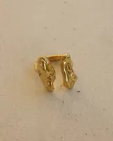Anillo de diseño orgánico y macizo, realizado artesanalmente en bronce. Presenta una estructura abierta con dos piezas de forma irregular y textura rugosa.