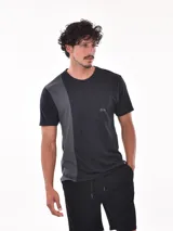 Remera negra de corte oversized con bolsillo en el pecho y detalle de bloque gris en el lateral.