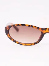 Lentes de sol con montura de carey y forma ovalada, con lentes marrones degradadas.