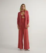 Blusa corta de tejido de punto color salmón, con cuello redondo, mangas largas, recortes frontales y detalle retorcido.