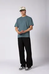 Pantalón de jogging de corte recto y fit relajado, confeccionado en tejido de algodón de color gris azulado. Presenta una caída amplia, cintura elástica y un pequeño logo bordado en la parte superior del muslo.