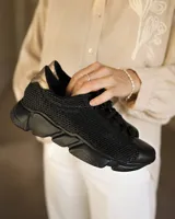 Championes urbanos de mujer con diseño combinado en cuero sintético y tejido de malla, color negro con detalle plateado en el talón y suela de goma robusta.
