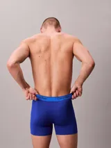 Pack de tres bóxers de hombre, uno celeste, uno azul y uno azul marino, con cintura elástica con logo Calvin Klein.