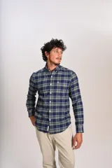 Camisa de manga larga confeccionada en tejido de franela con estampado de cuadros en tonos azul marino y verde. Presenta cuello abotonado, cierre frontal con botones y un bolsillo en el pecho con el logo bordado de la marca.