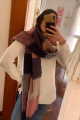 Bufanda de gran tamaño con diseño de cuadros en tonos naranja, rosa, gris, negro y beige, con flecos en los extremos.