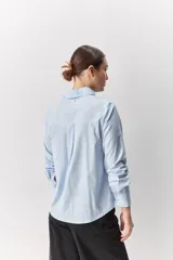 Camisa de algodón blanca, de calce relajado, con cuello clásico, mangas largas y cierre frontal con botones.