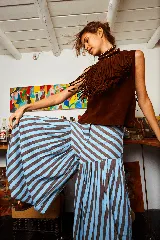 Pantalón babucha de lino con estampado a rayas verticales color celeste y marrón. Presenta corte amplio y tiras para atar en los tobillos.