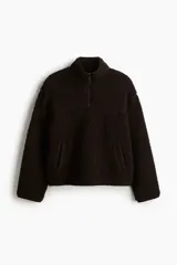 Buzo de sherpa con textura de peluche, cuello elevado y medio cierre frontal. Presenta hombros caídos, mangas largas y bolsillos laterales insertados.