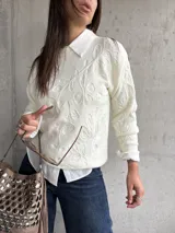 Sweater de punto color natural con diseño de relieve floral en toda la prenda, cuello redondo y mangas largas con puños acanalados.